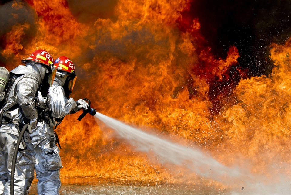 huge fire, firefighters in silver suit, fire hose spraying out water
