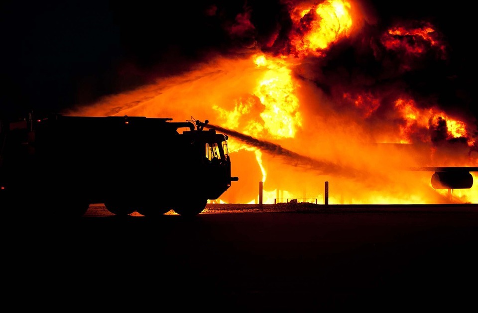 silhouette of a truck, water splashing from the firetruck, huge fire