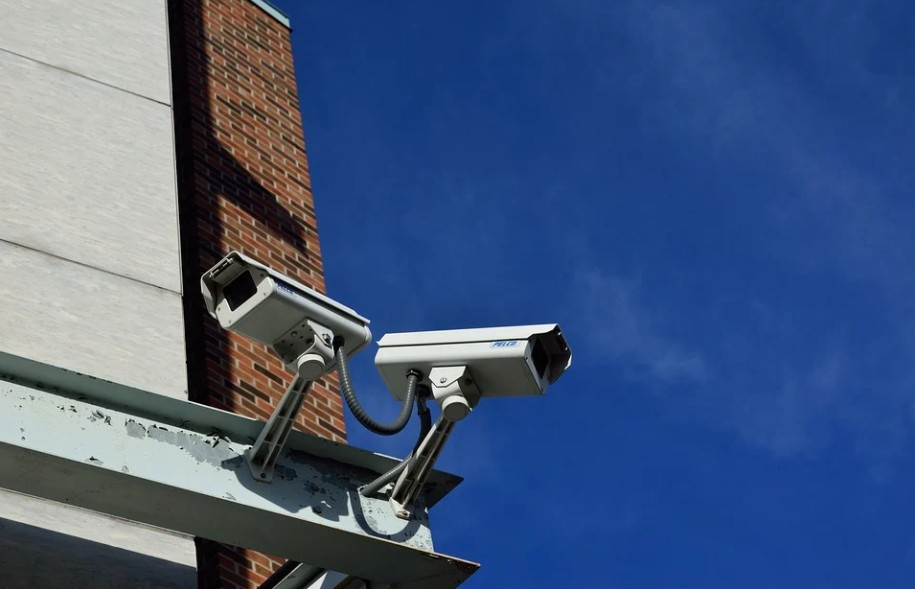 two-CCTV-cameras-bright-blue-sky-bricked-walls